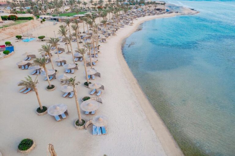Aerial view of the beach at Blend Elphistone Resort, with palm trees, straw parasols and the turquoise sea