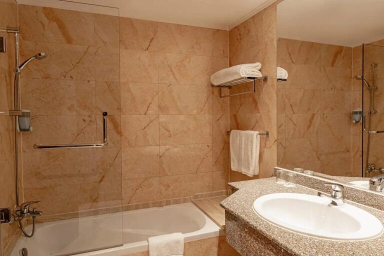 A marble bathroom with a bathtub, a shower and a sink