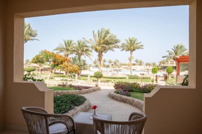 A terrace with two wicker armchairs, facing the flower gardens and palm trees of Blend Elphistone Resort