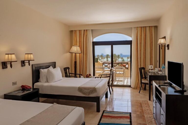 A twin room with a TV, a desk and a balcony facing the sea