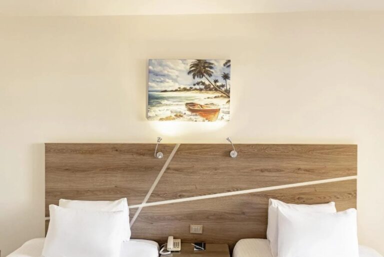 A wooden headboard under a painting of a boat on the beach