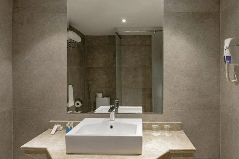 A bathroom with a square basin, a large mirror and a hairdryer