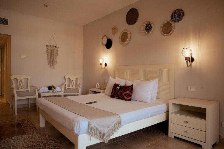 A double room with woven baskets on the wall and two white chairs