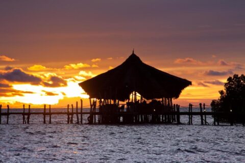 The thatched pavilion of Fundu Lagoon, on stilts at the end of the jetty, at sunset