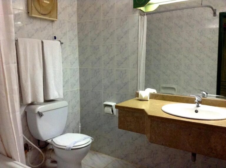 A gray-tiled bathroom with a countertop sink and a shower curtain