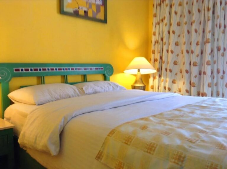 A bed with a green mosaic headboard, against a yellow wall