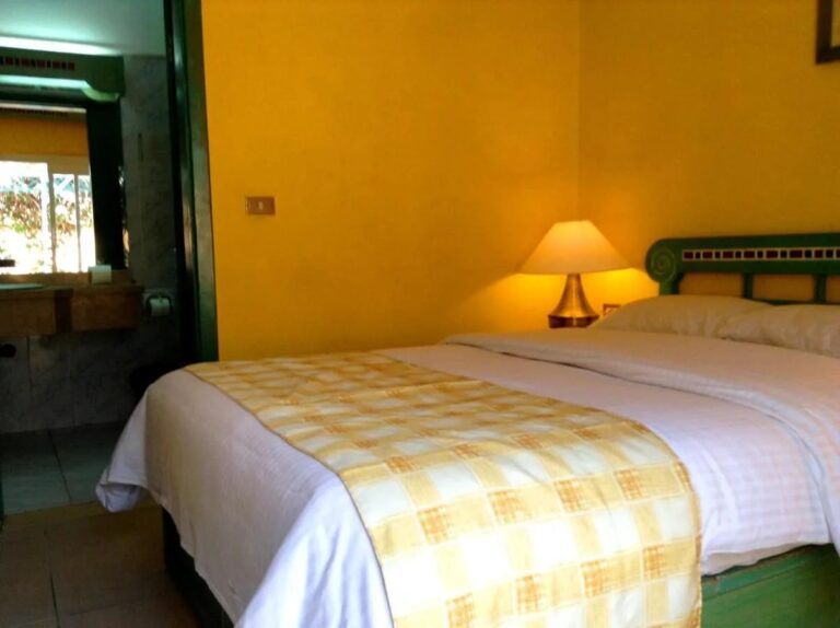A room with yellow walls, a double bed and the bathroom door open