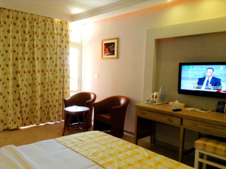 A room with two leather armchairs, a desk and a TV