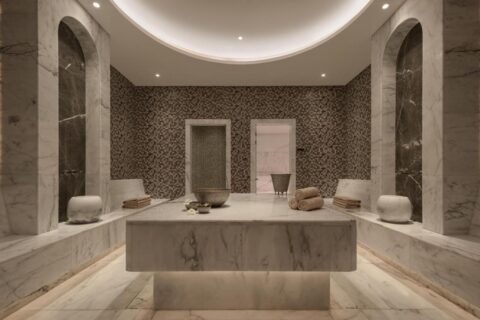 A marble-clad spa room at JAZ Elite Riviera, with a wide stone table in the center