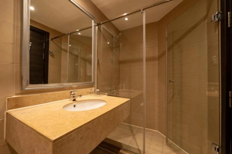 A bathroom with a basin, a large mirror and a glass shower