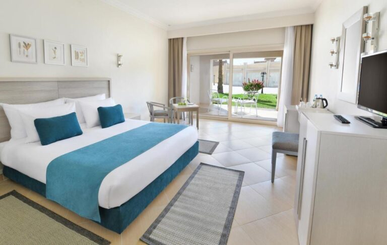 A double room with light furniture, opening onto a terrace and a flowering lawn