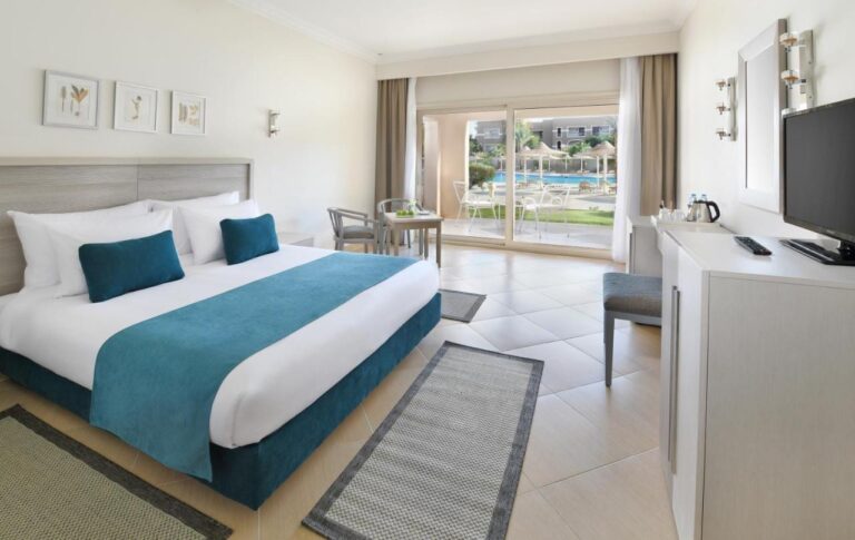 A double room with light furniture, opening onto a terrace facing the pool