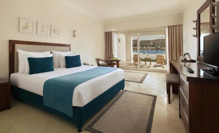 A double room with dark wood furniture, with a terrace facing the pool