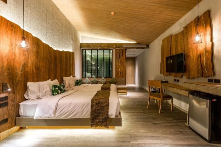 A twin room with a raw wood headboard, a desk and a TV
