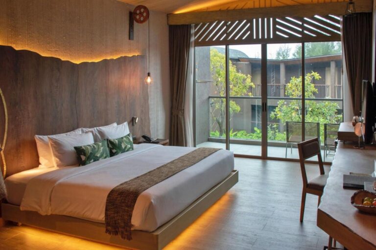 A double room opening onto a balcony, facing the trees and another building