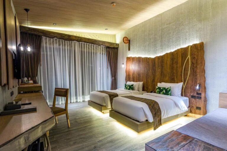 A twin room with beds lit from below, a desk and sheer curtains