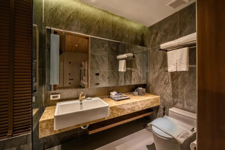 A gray stone bathroom with a basin on a marble counter and a large mirror