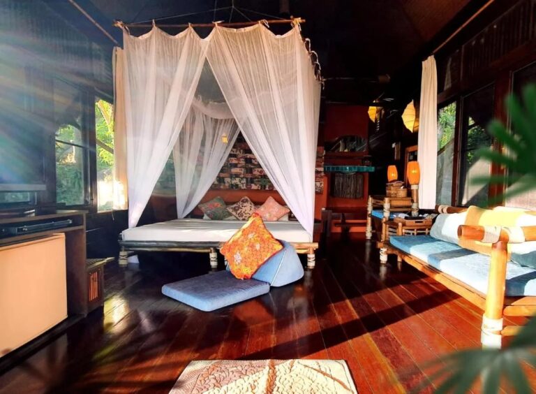 The bed under a mosquito net and the bench of a cottage, lit by the sun