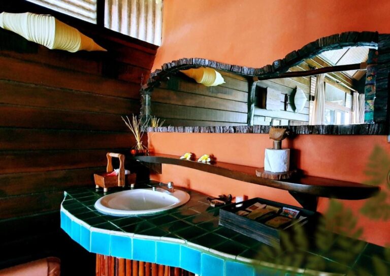 A basin on a turquoise mosaic counter, under a wood-framed mirror