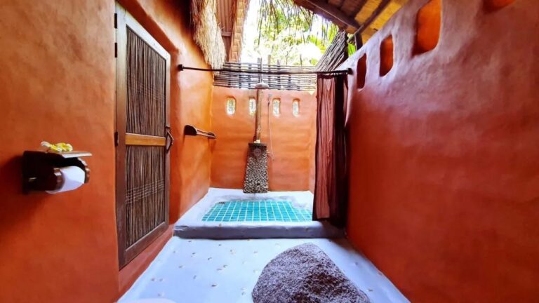 The semi-open shower of a cottage, with a curtain and a turquoise mosaic floor