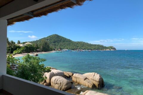 The bay and its rocks seen from a covered terrace at Koh Tao Heritage, with boats at anchor
