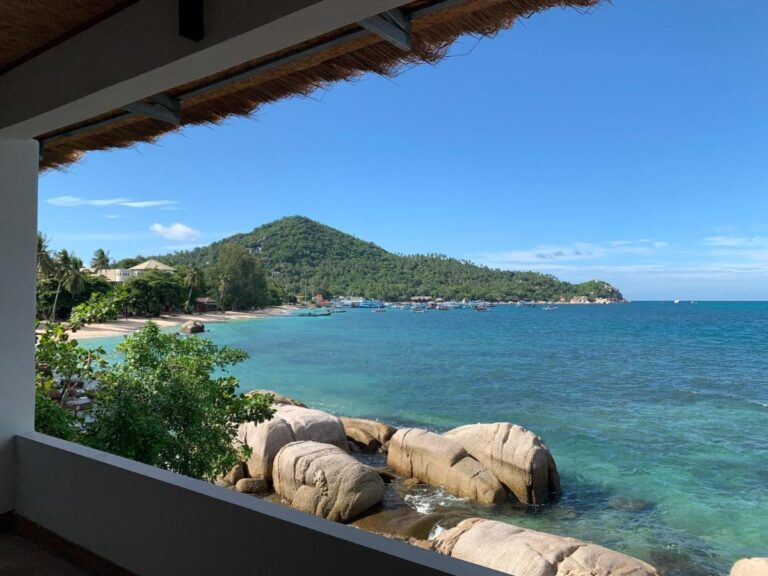 The bay and its rocks seen from a covered terrace at Koh Tao Heritage, with boats at anchor