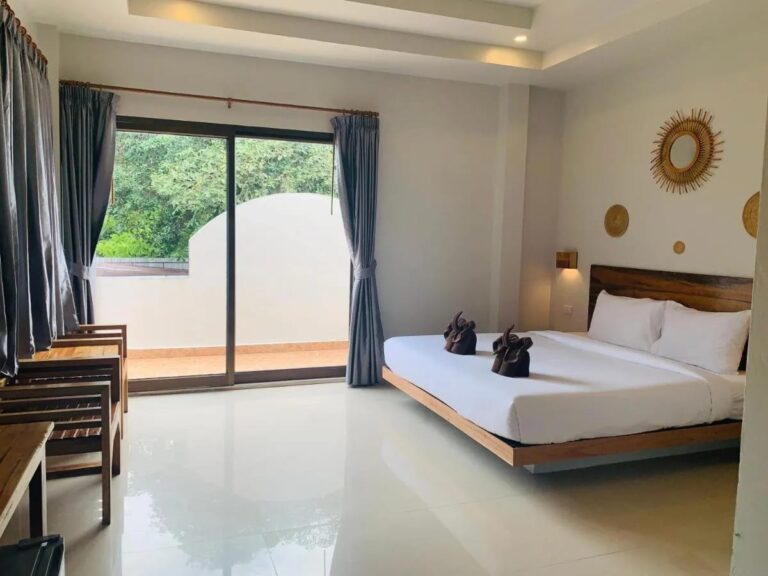 A double room with a picture window onto a balcony and wooden armchairs