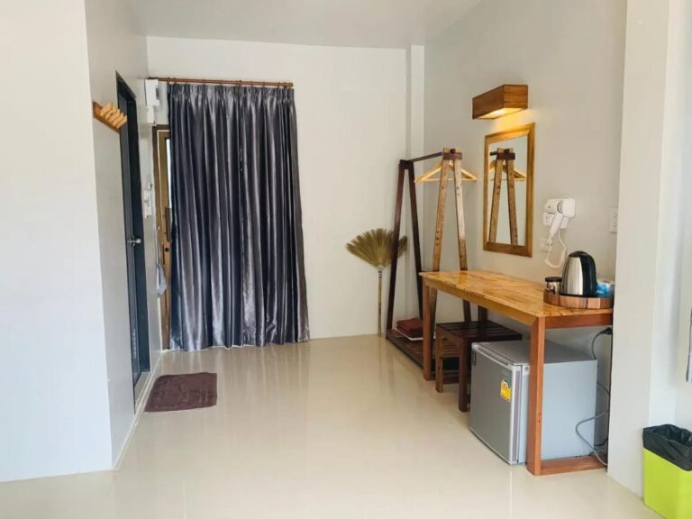 The entrance of a room, with a gray curtain, a clothes rack and a wooden desk