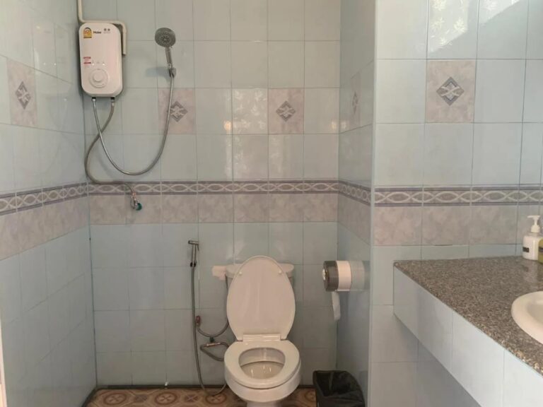 A tiled bathroom with a shower and water heater, a toilet and a sink