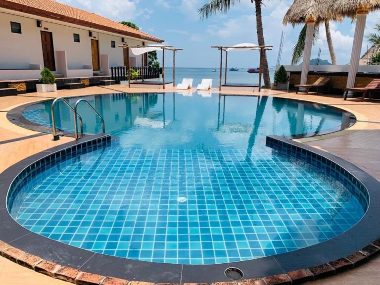 The blue-tiled pool, with the sea and boats in the background