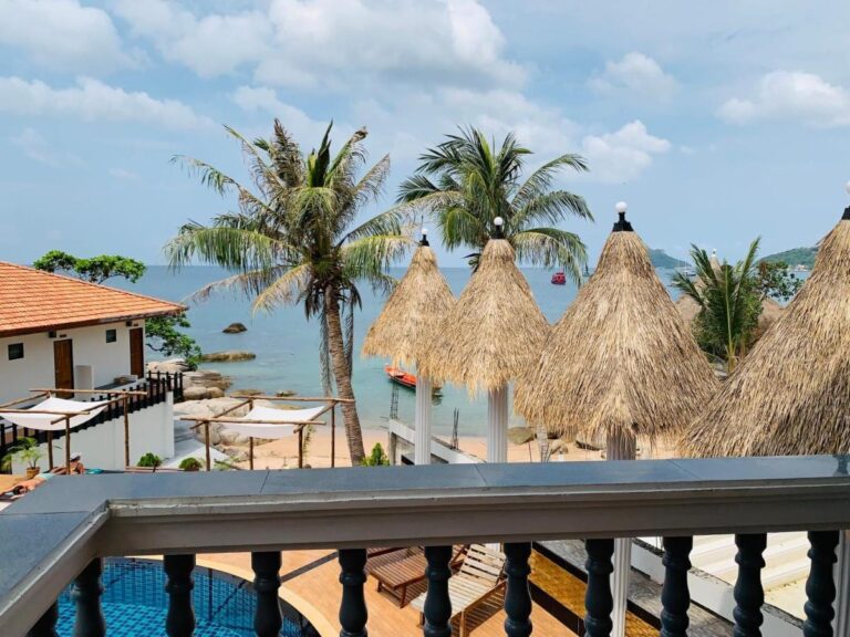 View from a balcony over the straw parasols, the palm trees and the sea