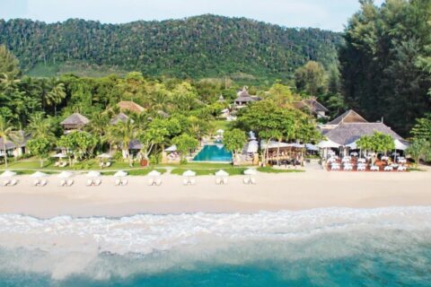 Layana Resort seen from the sea, with its beach, white parasols, pool and roofs under the palm trees