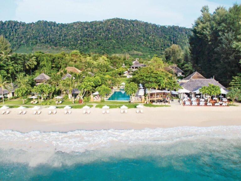 Layana Resort seen from the sea, with its beach, white parasols, pool and roofs under the palm trees