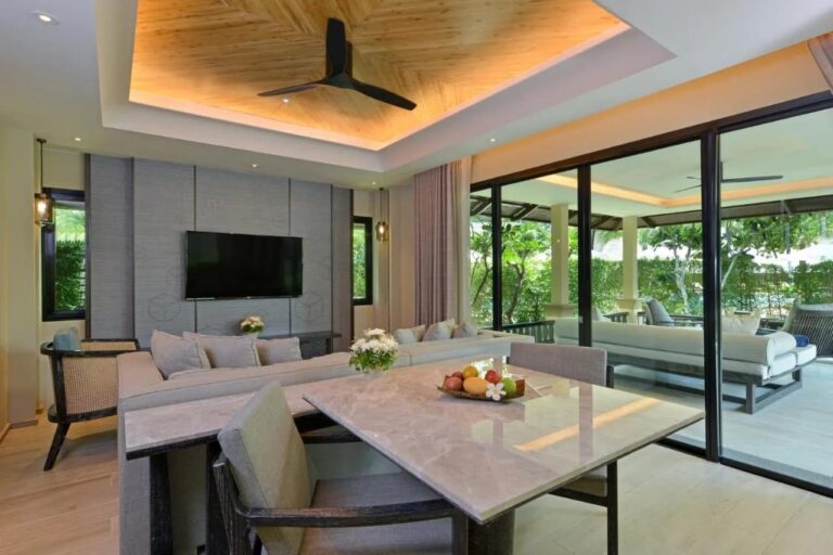 A living room with a marble table and a sofa, opening onto a covered terrace