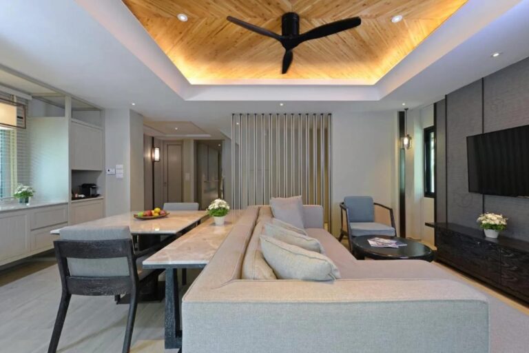 A living room with a long sofa, a marble table and a coffee machine