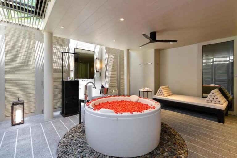 A round bathtub filled with red petals, set on pebbles