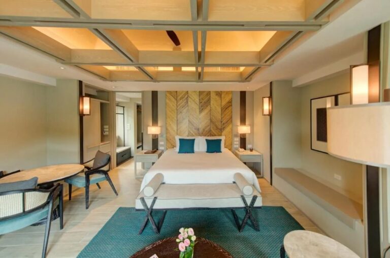 A double room in front of a herringbone wood panel, with a bench and a blue-green rug