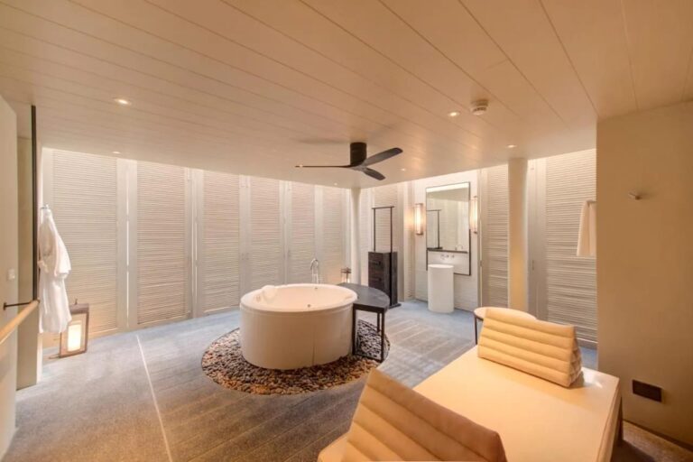 A bathroom at Layana Resort with a round bathtub on pebbles and a hanging bathrobe