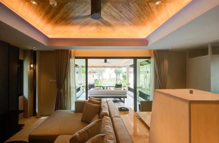 A living room with a wooden ceiling, opening onto a covered terrace and the garden