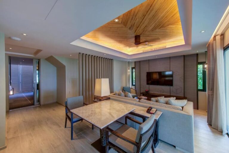 A living room with a marble table, a large sofa and a wall-mounted TV