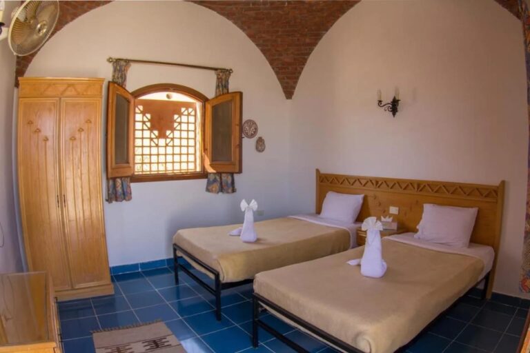 A twin room under a brick vault, with a wardrobe and wooden shutters