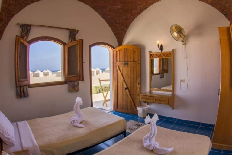 A twin room opening onto the beach, with white tents and the sea in the background