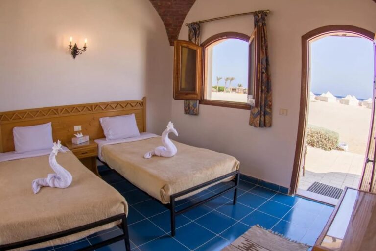A twin room under a brick vault, with the door open onto the sand