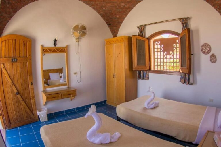 A twin room with a wooden door, a mirror and a wardrobe