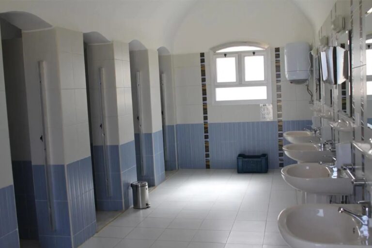 A shower block with a row of stalls and a line of sinks