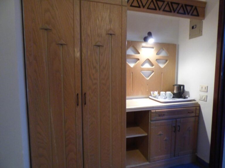 A large wooden wardrobe and a cabinet with a kettle and cups