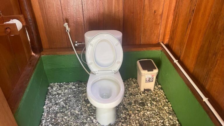 A toilet with wooden walls and a pebble floor