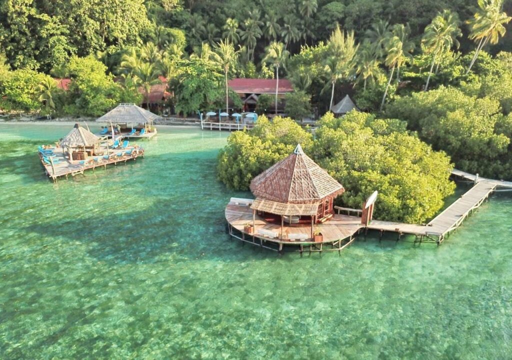 Aerial view of Raja Ampat Dive Lodge, its jetties on stilts and its red roofs under the palm trees