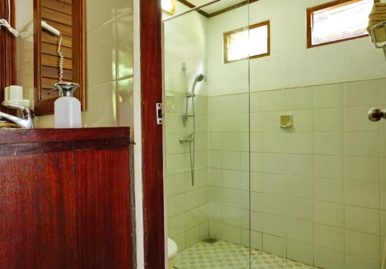 A bathroom with a wooden vanity and a shower behind a glass panel