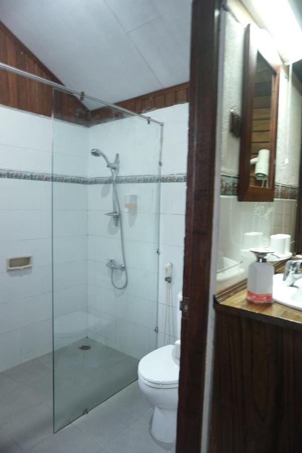 A white-tiled bathroom with a glass shower and a toilet